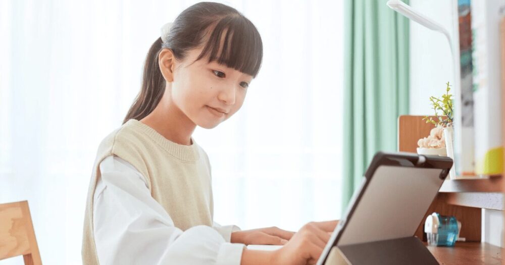 学級閉鎖中にタブレットでオンライン学習をする女の子